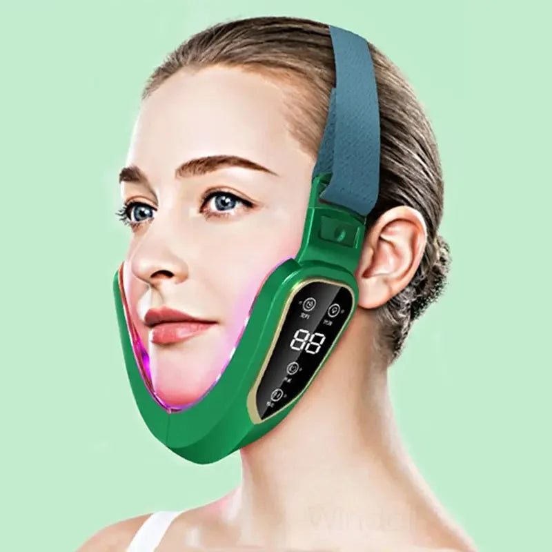 Woman wearing green LED light therapy facial slimming mask with digital display on light green background