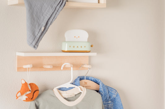 A baby's room decor with clothes and shelves.
