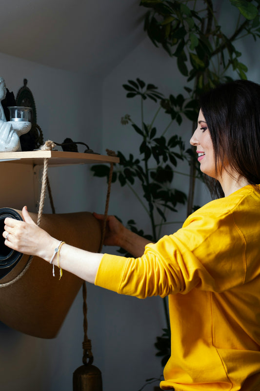 Woman in yellow shirt arranging plants indoors