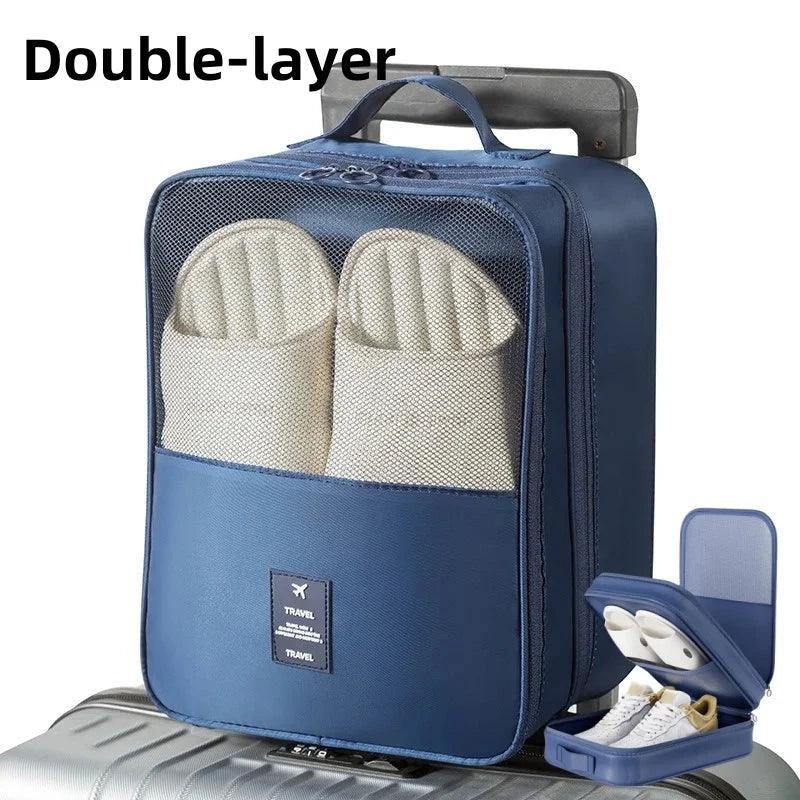 Blue double-layer travel shoe bag with mesh front holding slippers on top of suitcase