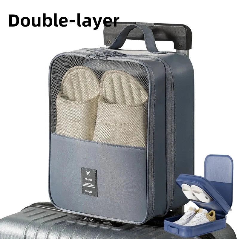 Double-layer travel storage bag with mesh pocket holding slippers, placed on silver suitcase with handle