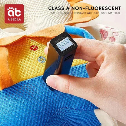 Hand holding black digital detector measuring radiation on colorful blue and yellow fabric toy