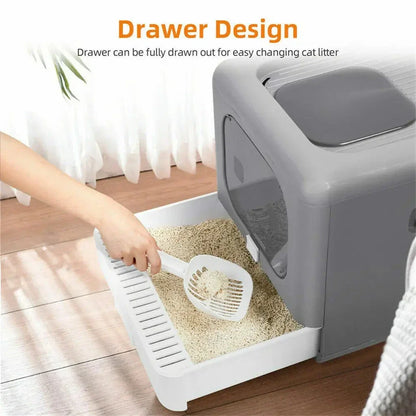 Hand scooping cat litter from drawer-style gray and white cat litter box on wooden floor
