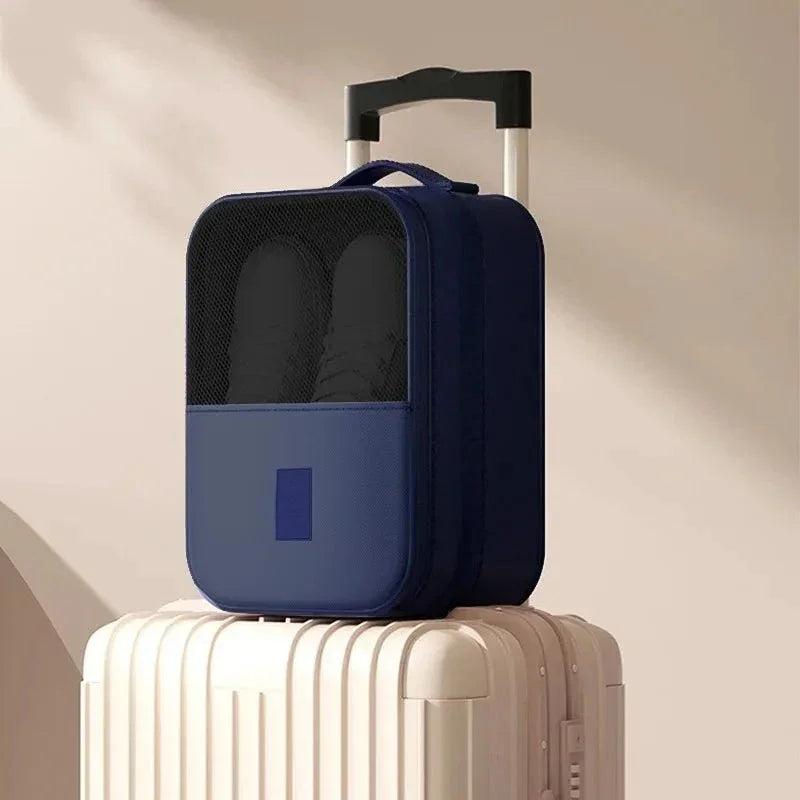 Compact navy blue travel shoe bag on top of beige hard shell suitcase with telescopic handle