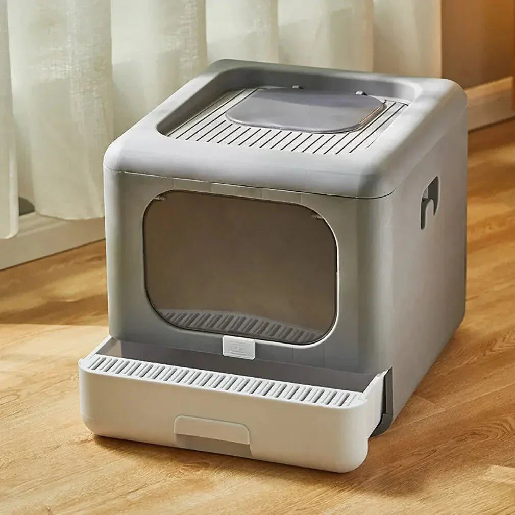 Modern gray enclosed cat litter box with front opening and pull-out tray on wooden floor