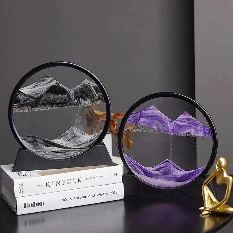 Decorative round sand art frames with black and purple sand mountains on books beside golden human figure sculpture