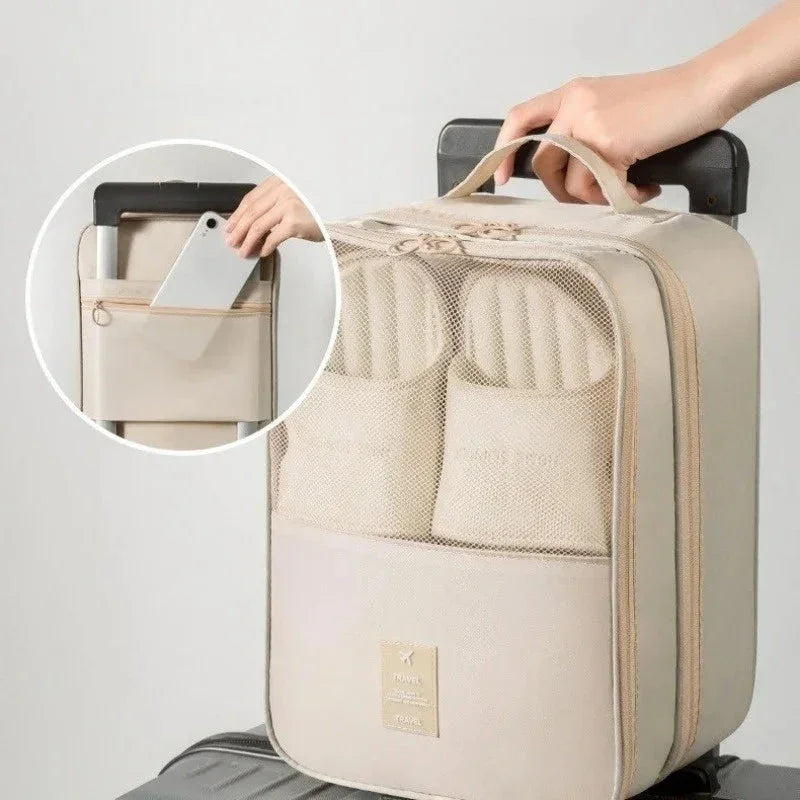 Beige travel organizer bag with mesh pocket holding slippers on trolley luggage with phone pocket
