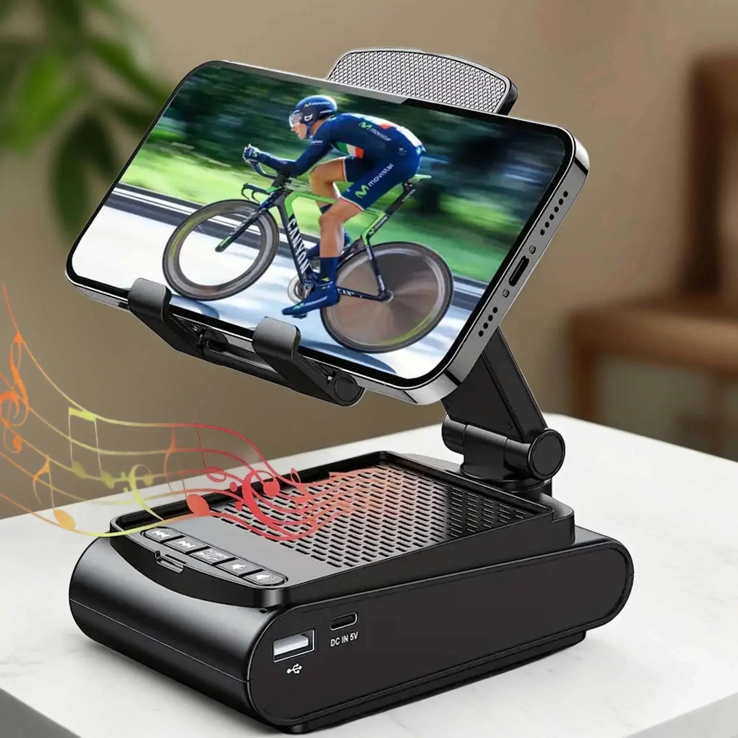 Black adjustable phone holder with built-in speaker on white surface displaying cyclist video