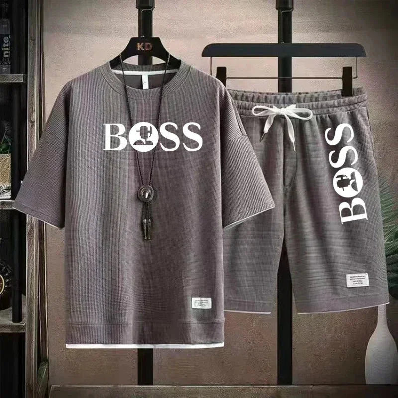 Grey short sleeve shirt and shorts set with white BOSS logo, hanging on black hangers