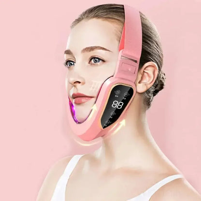 Woman wearing pink V-line face slimming massager with digital display on pink background