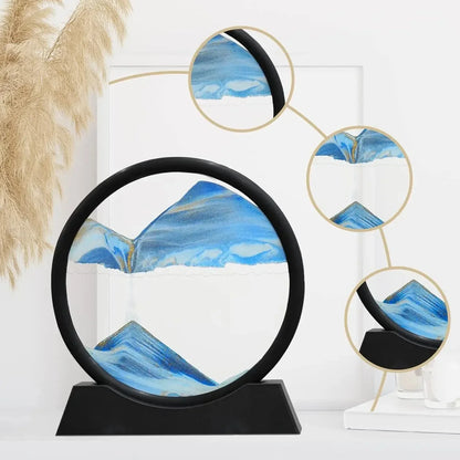 Modern round blue and white sand art hourglass with black frame on white surface and pampas grass