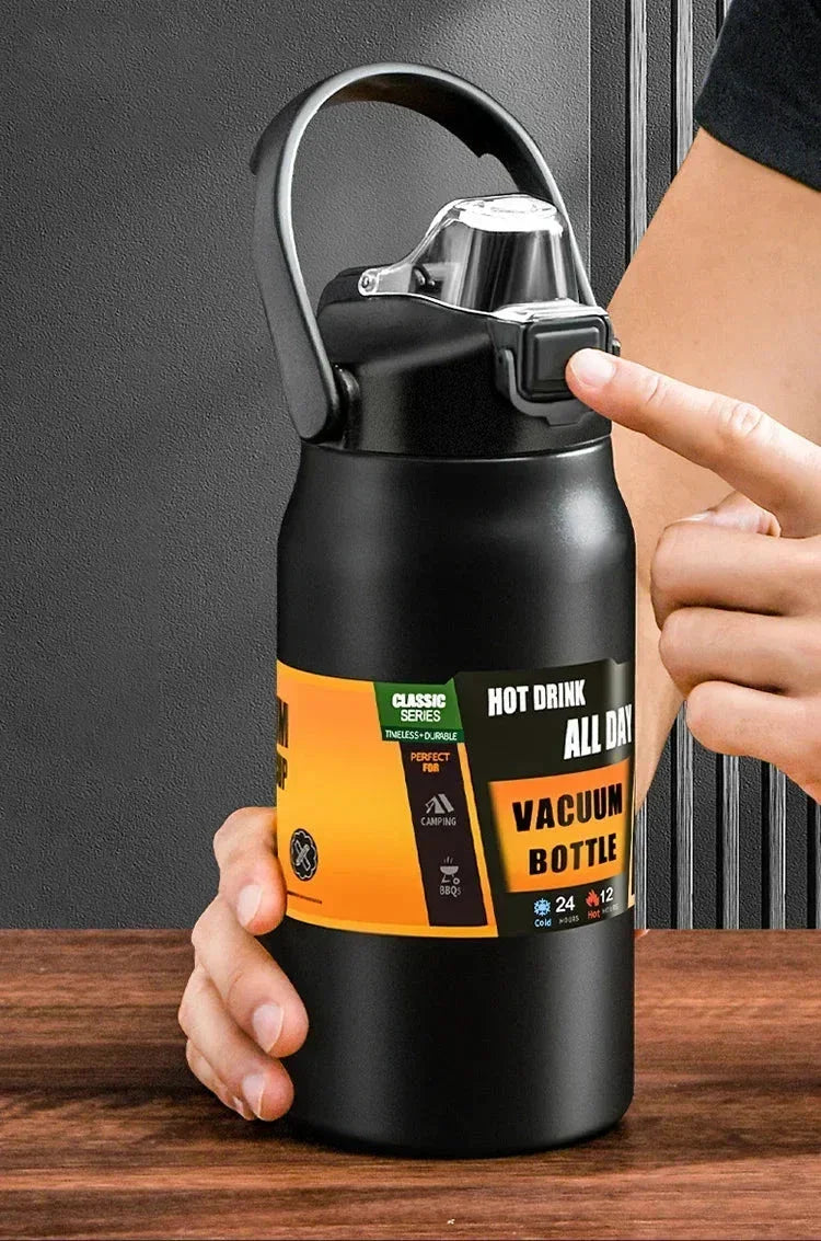 Black vacuum bottle with orange label, hand holding and finger pressing lid button on wooden table